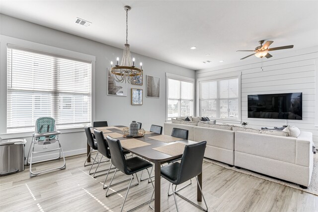 dining room featuring ceiling fan with notable chandelier, light hardwood / wood-style flooring, and a healthy amount of sunlight