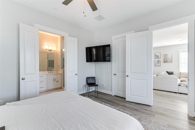 bedroom with sink, connected bathroom, light wood-type flooring, and ceiling fan