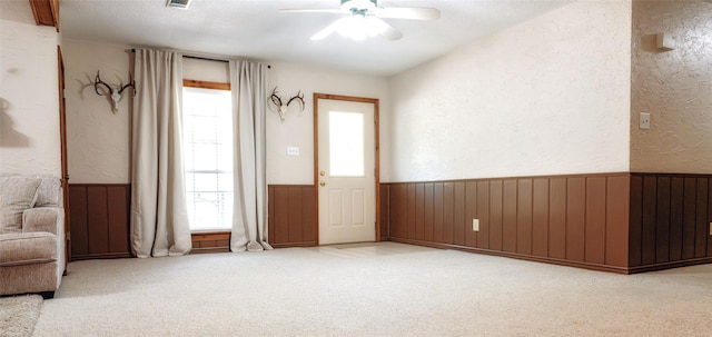 interior space with ceiling fan and wooden walls