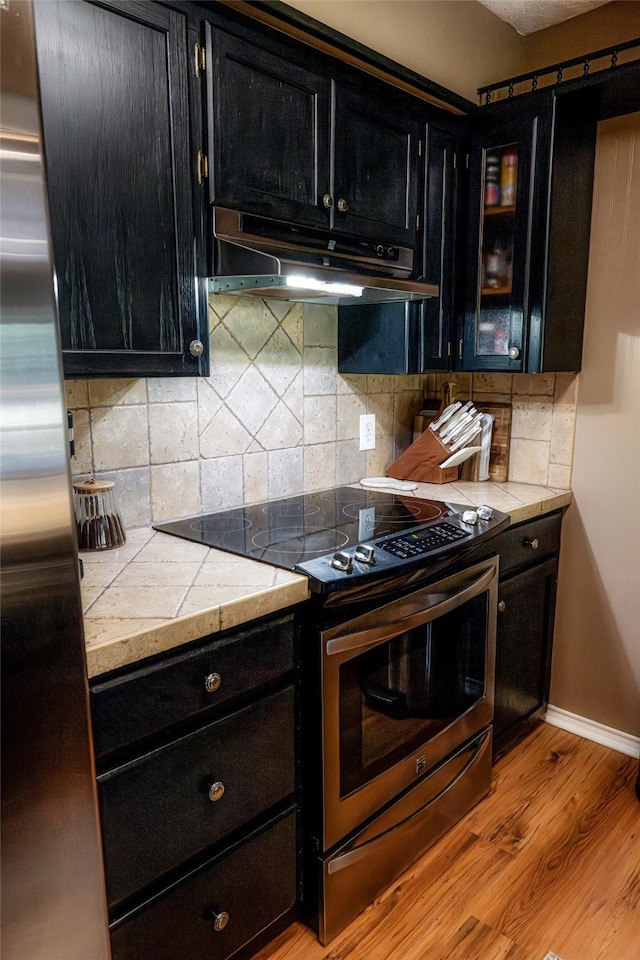 kitchen featuring backsplash, tile counters, stainless steel appliances, and light hardwood / wood-style flooring