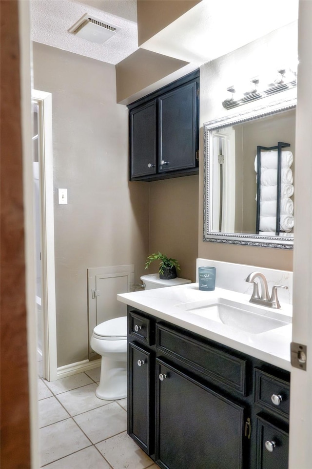 bathroom featuring tile patterned flooring, a textured ceiling, vanity, and toilet