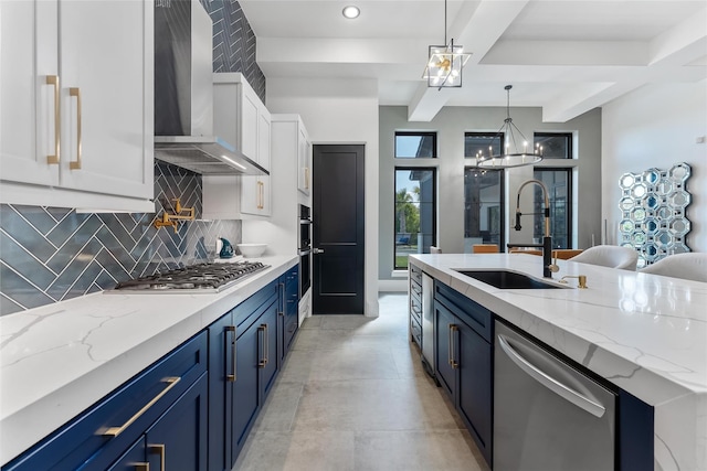 kitchen featuring wall chimney exhaust hood, sink, stainless steel appliances, hanging light fixtures, and white cabinetry