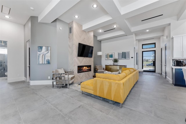 living room featuring a premium fireplace, coffered ceiling, beamed ceiling, and a wealth of natural light