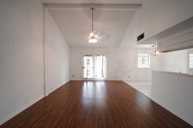 empty room with vaulted ceiling, ceiling fan with notable chandelier, hardwood / wood-style floors, and a healthy amount of sunlight