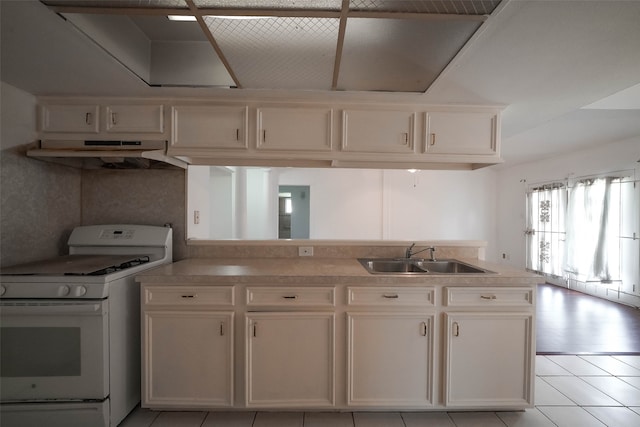 kitchen with light tile patterned flooring, extractor fan, sink, white range with gas cooktop, and white cabinetry