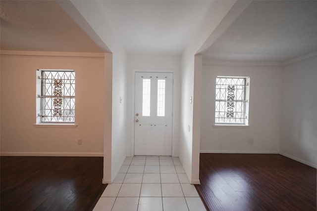 entrance foyer with ornamental molding, light hardwood / wood-style floors, and a wealth of natural light