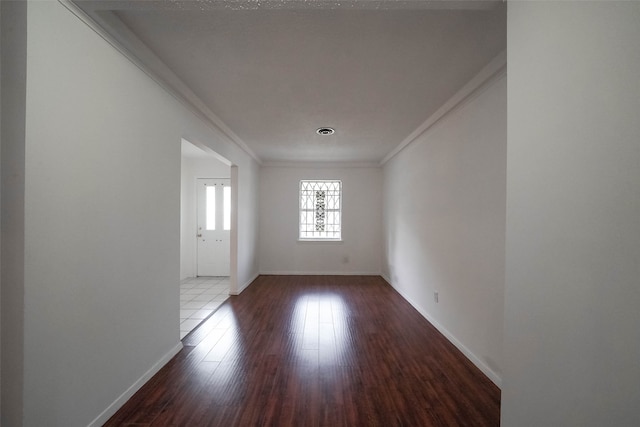 empty room with ornamental molding and dark hardwood / wood-style flooring