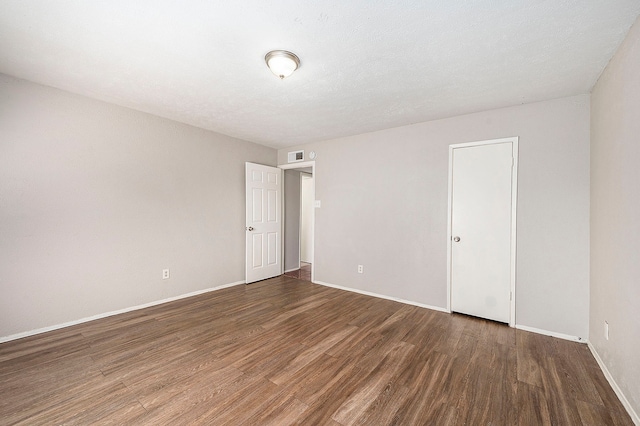 spare room featuring dark hardwood / wood-style flooring and a textured ceiling