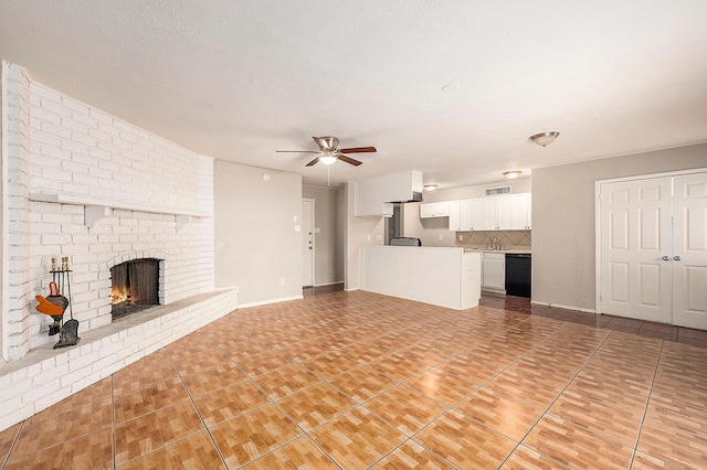 unfurnished living room with ceiling fan, sink, a fireplace, tile patterned flooring, and a textured ceiling