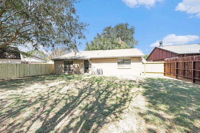 rear view of property featuring cooling unit and a lawn