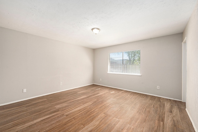 empty room featuring wood-type flooring and a textured ceiling