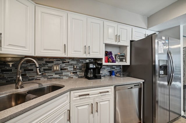 kitchen with light stone counters, decorative backsplash, stainless steel appliances, sink, and white cabinetry