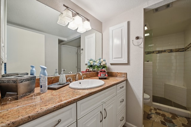 bathroom featuring a tile shower, tile patterned floors, vanity, and toilet