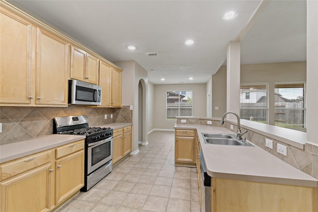 kitchen with sink, stainless steel appliances, decorative backsplash, light brown cabinetry, and light tile patterned floors