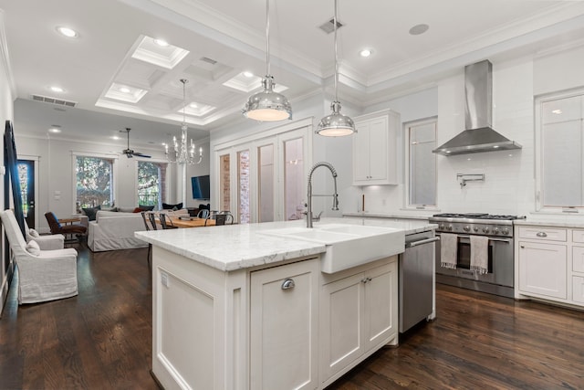 kitchen featuring sink, light stone counters, a center island with sink, stainless steel appliances, and wall chimney range hood