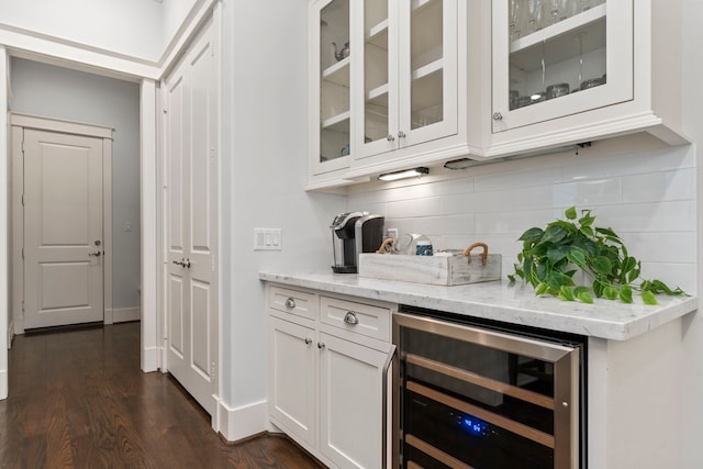 bar with white cabinetry, backsplash, light stone countertops, dark hardwood / wood-style flooring, and beverage cooler