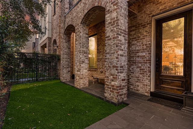 view of exterior entry featuring a lawn