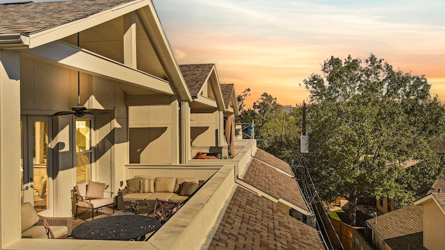 property exterior at dusk with an outdoor living space and a balcony