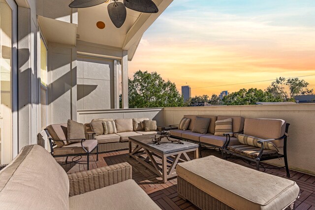 patio terrace at dusk featuring outdoor lounge area and a balcony