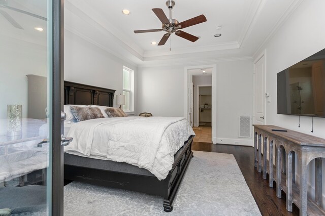 bedroom featuring ceiling fan, dark hardwood / wood-style floors, crown molding, and a tray ceiling