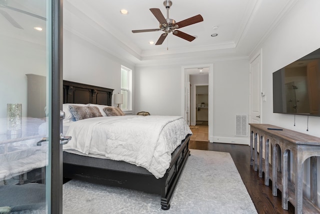 bedroom with ceiling fan, ornamental molding, dark hardwood / wood-style floors, and a raised ceiling