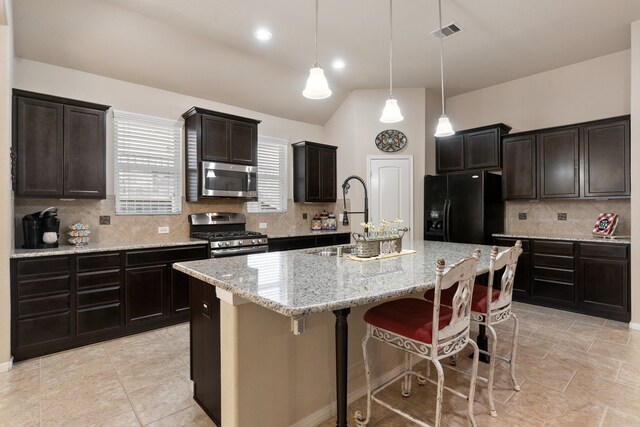 kitchen with a center island with sink, appliances with stainless steel finishes, decorative light fixtures, and backsplash