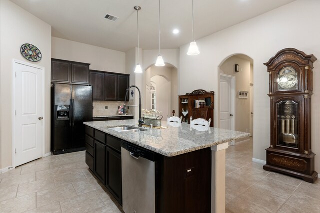 kitchen with black refrigerator with ice dispenser, a center island with sink, dishwasher, dark brown cabinetry, and sink