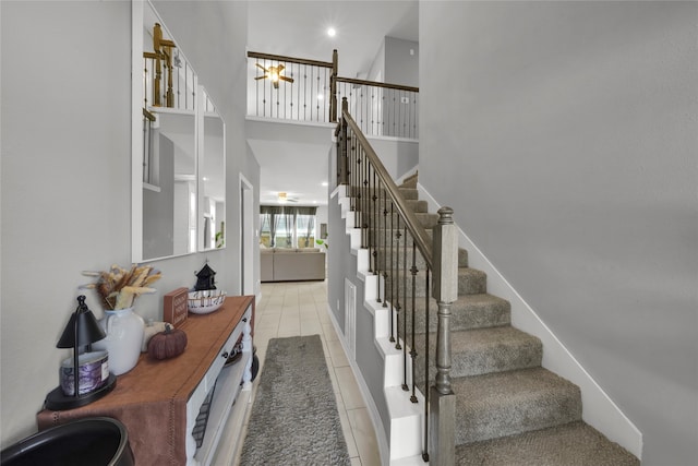 stairway with a towering ceiling and tile patterned floors