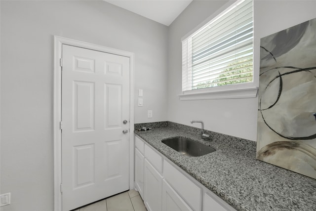 kitchen with light stone counters, sink, light tile patterned floors, and white cabinets