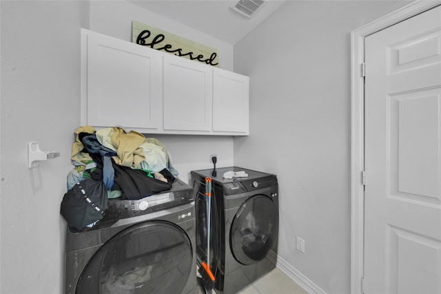 clothes washing area with cabinets, light tile patterned floors, and washing machine and clothes dryer