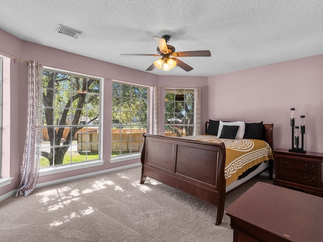 carpeted bedroom with multiple windows, ceiling fan, and a textured ceiling