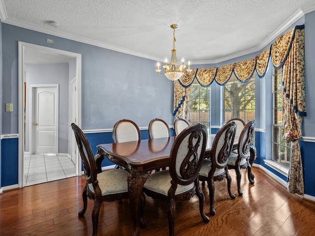 dining space featuring hardwood / wood-style floors, a chandelier, a textured ceiling, and ornamental molding