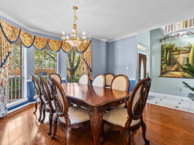 dining area with ornamental molding, a textured ceiling, hardwood / wood-style flooring, and a notable chandelier