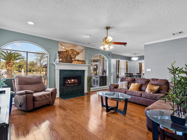 living room with crown molding, a fireplace, wood-type flooring, and a textured ceiling