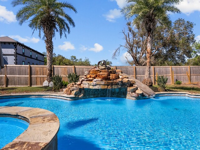 view of pool with pool water feature and a hot tub