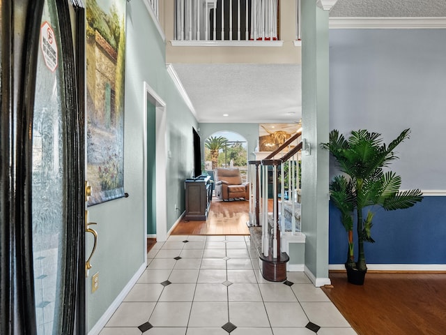 foyer featuring a textured ceiling, light hardwood / wood-style flooring, and ornamental molding