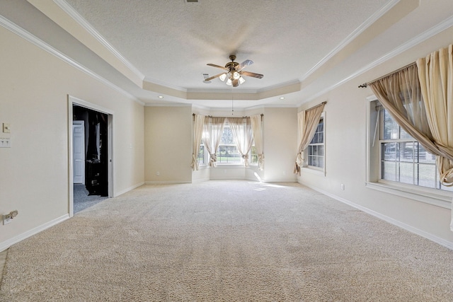 carpeted empty room with ceiling fan, a textured ceiling, a raised ceiling, and crown molding