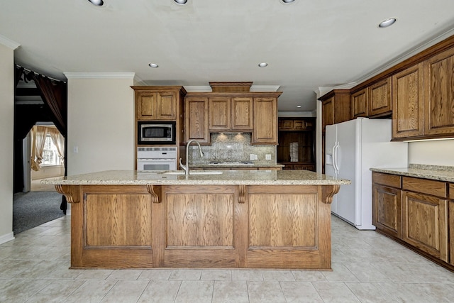 kitchen featuring light stone countertops, a center island with sink, white appliances, and a breakfast bar