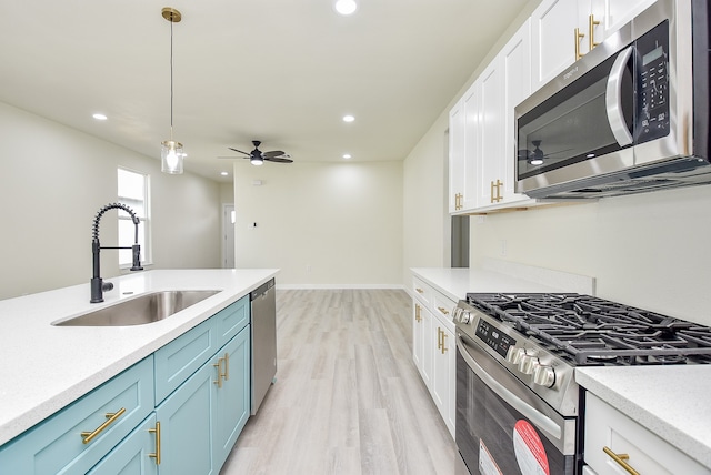 kitchen featuring blue cabinets, white cabinets, sink, stainless steel appliances, and light hardwood / wood-style floors