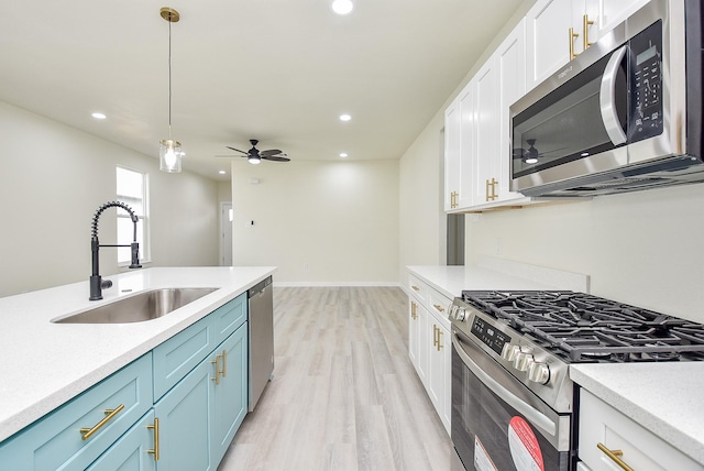 kitchen with a sink, light wood-style flooring, white cabinetry, and stainless steel appliances