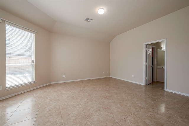 tiled spare room featuring a wealth of natural light and lofted ceiling