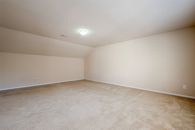 additional living space featuring light colored carpet and lofted ceiling