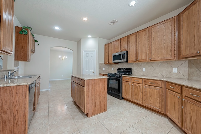 kitchen with decorative backsplash, appliances with stainless steel finishes, sink, light tile patterned floors, and a kitchen island