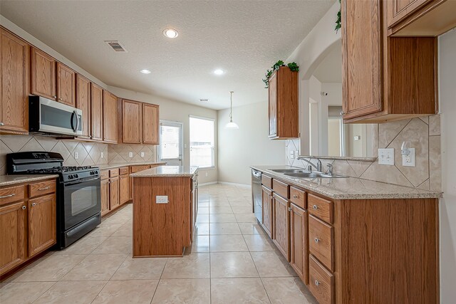 kitchen featuring sink, hanging light fixtures, stainless steel appliances, light tile patterned floors, and a kitchen island