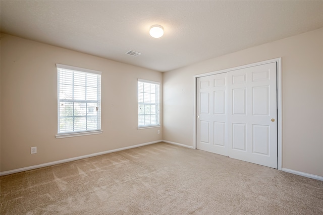 unfurnished bedroom featuring a closet and light colored carpet