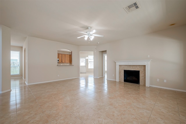 unfurnished living room with ceiling fan, a fireplace, and light tile patterned flooring