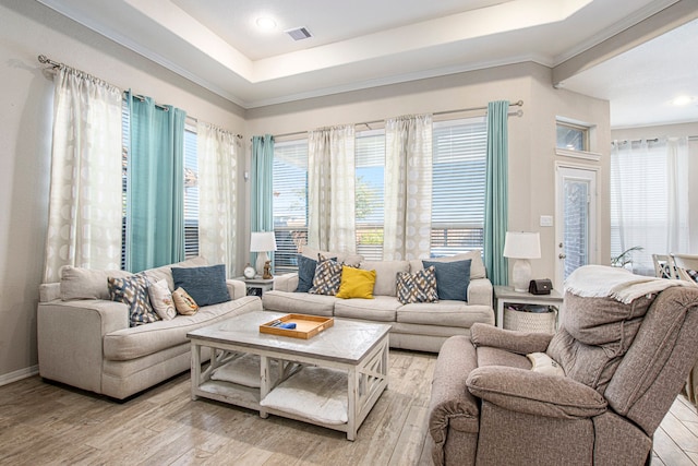 living room featuring light wood-type flooring, a tray ceiling, and ornamental molding