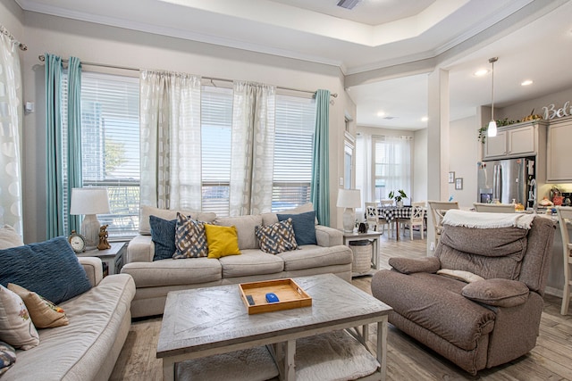 living room featuring a healthy amount of sunlight, light wood-type flooring, and crown molding