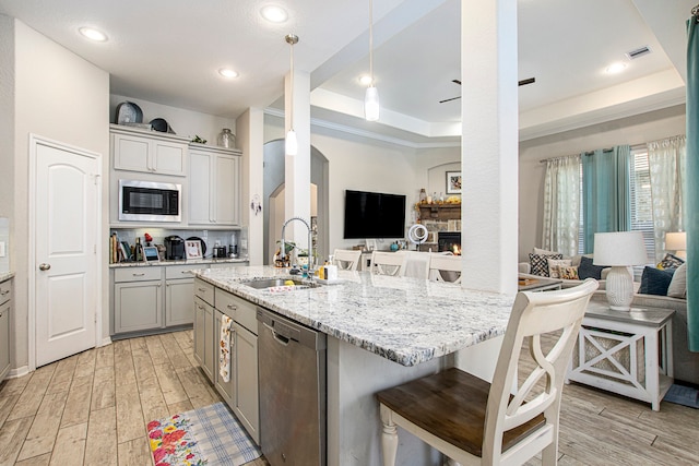 kitchen featuring light hardwood / wood-style floors, sink, gray cabinets, a breakfast bar, and appliances with stainless steel finishes