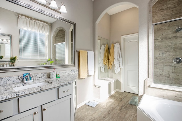 bathroom with hardwood / wood-style flooring, vanity, and plus walk in shower